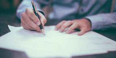 Man in a blue shirt writing down notes on a piece of paper