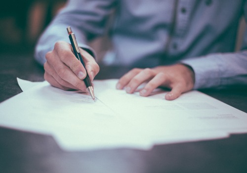 Man in a blue shirt writing down notes on a piece of paper