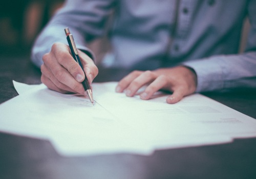 Man writing on paperwork dealing with an insurance claim